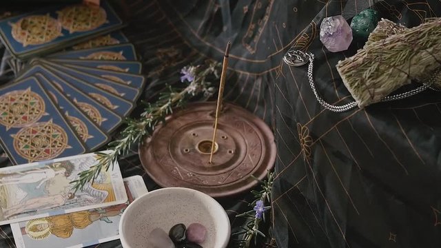 Slow zoom out of altar with incense, gemstones, tarot and sage