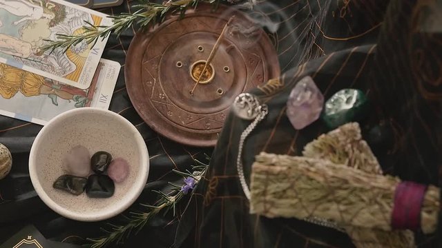 Slow zoom out of altar with incense and hands placing crystals