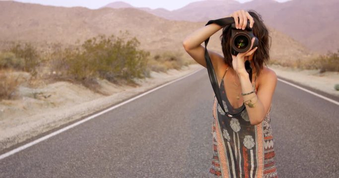 Trendy female photographer taking photos on desert highway