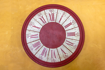 The empty face of clock without clock hands on yellow wall.