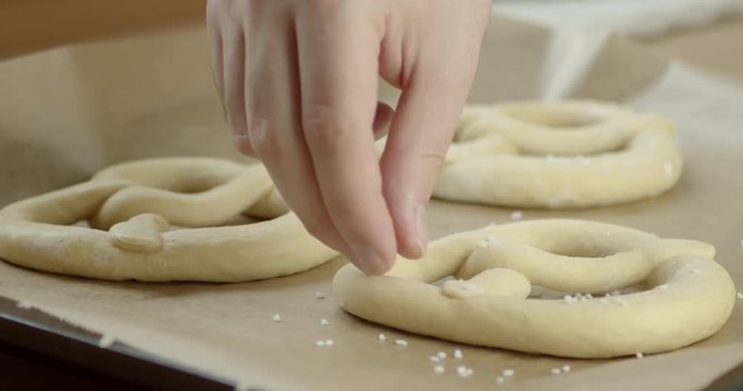 Closeup shot of a hand placing salt on a frozen Pretzel.
