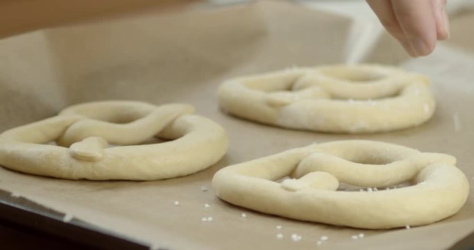 Slowmo, hand placing salt on frozen pretzels at home.