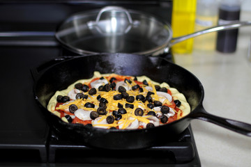 Pizza with pepperoni, mushrooms, and black olives ready to bake in the oven.