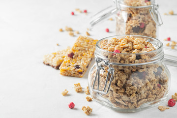 Homemade granola with berries in a mason jar on white background.
