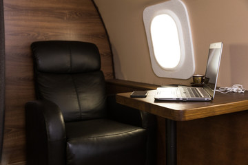 laptop on the table in the interior of a private jet. Flying first class.