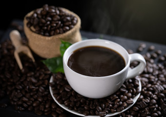 Hot coffee cup with coffee beans on the wooden table