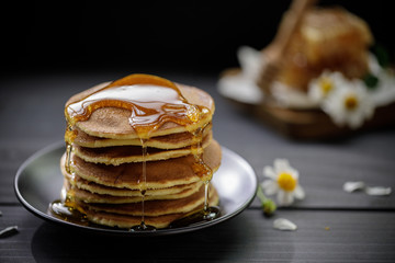 Honey dripping on the stack of pancakes for breakfast on the wooden table, healthy products by organic natural ingredients concept