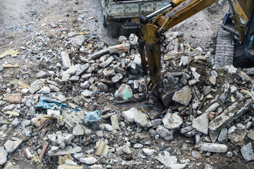 Backhoe excavator and truck clearing wreckage, demolish or remove a building.