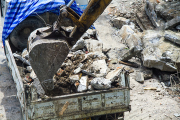 Backhoe excavator and truck clearing wreckage, demolish or remove a building.
