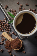 Hot coffee cup with coffee beans and the ground powder of coffee on the wooden table