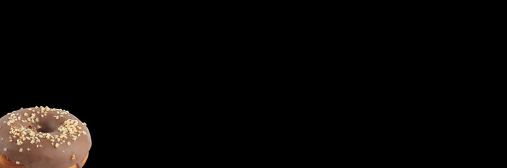 Appetizing donut in chocolate icing with nuts on a black background. Isolated. Banner.
