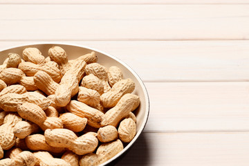 Roasted peanuts in a pan on a white wooden background. Place for text. Top view.