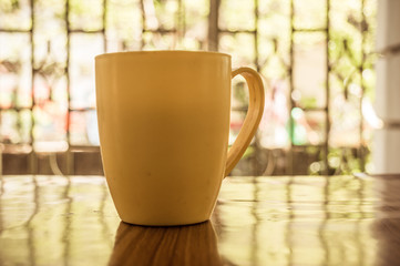 Closeup image of a cup of Cappuccino, mocha, latte, Americana, espresso hot coffee aroma for on rustic wooden table background in cafe with backdrop of sunlight light coming from window in morning.