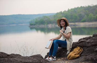Beautiful women with books sitting on a rocky courtyard along the reservoir