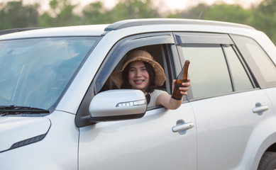 A beautiful woman holding a drink bottle extending out of the car