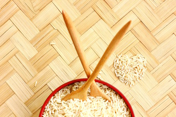organic rice on bamboo floor .raw rice in heart pattren with wooden spoon,fork on bamboo floor .topview,copy space.