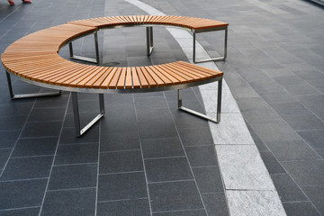 Round wooden and aluminum bench for public urban space.