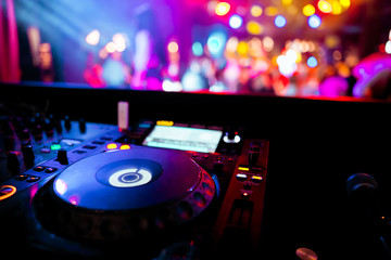 DJ remote on stage at the nightclub. background of dancing people.