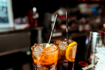 Cocktail whiskey cola with ice in a glass. On a wooden board are fragments of fruit. Photo with depth of field.