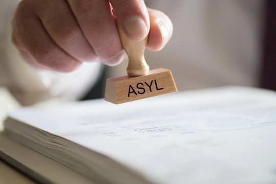 Ein Mann und ein Stempel mit dem Aufdruck Asyl