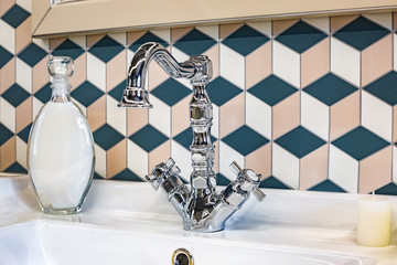 Soap and shampoo dispensers on Water tap sink with faucet in expensive loft kitchen