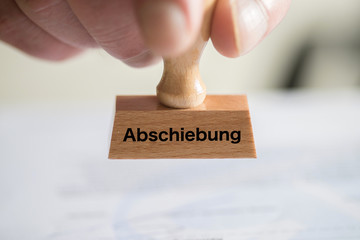 Ein Angestellter bei Ausländerbehörde und ein Stempel mit dem Aufdruck Abschiebung