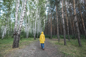 Obraz premium A woman in a yellow raincoat in the woods.
