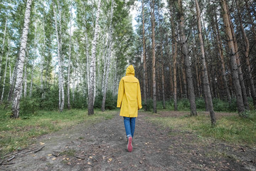 Fototapeta premium A woman in a yellow raincoat in the woods.
