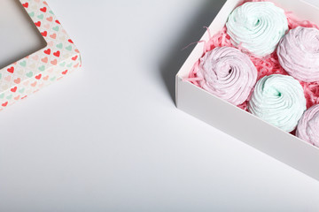 Homemade marshmallows of different colors are beautifully packed in a gift box. Nearby is the lid of the box with a transparent window.