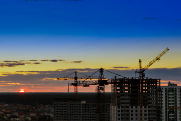 Industrial construction cranes on amazing sunset sky background