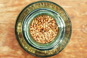 Brown flax seeds in jug, top view macro
