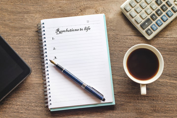 Resolutions to life text on book note with cup of coffee, pen and