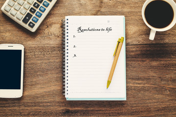 Resolutions to life text on book note with cup of coffee, pen and