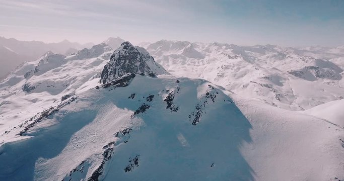 Aerial, decreasing, drone shot, around a snowy alpine mountain, overlooking lots of wintry alp peaks, on a sunny, winter day, in the swiss alps, in Switzerland