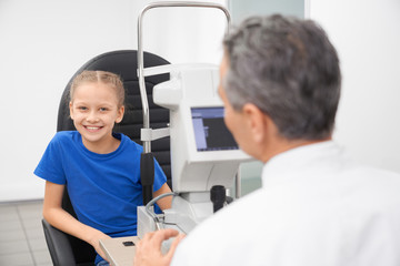 Young girl in opticial office examining eyesight.