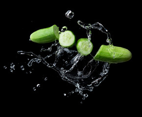 Fototapeta na wymiar Sliced cucumber with splashing water or explosion flying in the air isolated on black background