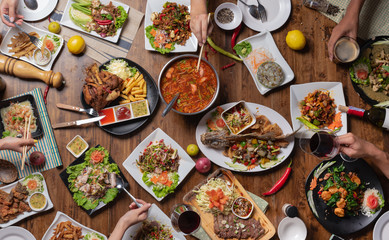 Top view, Group of people sitting at the wooden table with Steak, Fish, Vegetables and Spices,Thai food