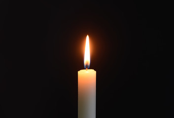 Burning candle on black background