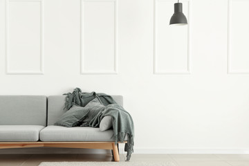 Soft sofa near white wall in room