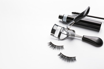 Mascara with false eyelashes and curler on white background