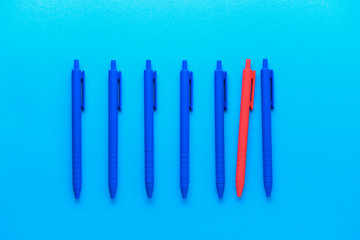 Red pen among blue ones on color background. Concept of uniqueness