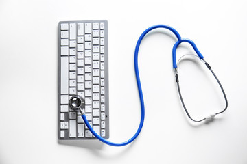 Stethoscope and computer keyboard on white background. Concept of online medical consultation