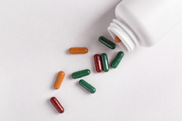 Overturned jar with plant based pills on white background