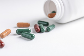 Overturned jar with plant based pills on white background