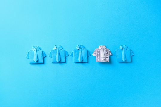 Origami shirt made of dollar banknote among paper ones on color background. Concept of uniqueness