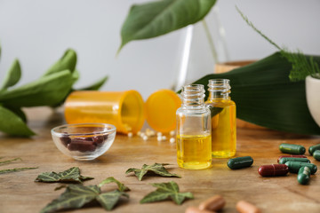 Plant based pills and essential oil on wooden table