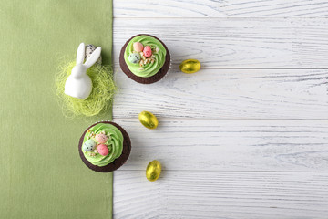 Tasty Easter cupcakes with candies on white table