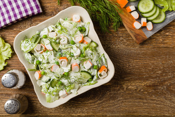 Crab sticks salad with peas, cucumber and mayonnaise.