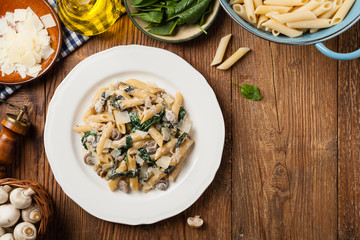 Penne pasta with spinach and mushrooms. Sprinkled with cheese.