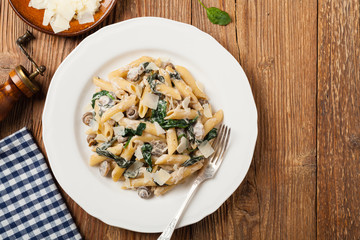Penne pasta with spinach and mushrooms. Sprinkled with cheese.